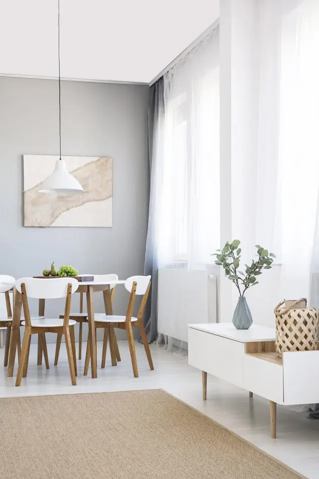 Bonito salón comedor decorado con estilo nórdico y microcemento gris en la pared 