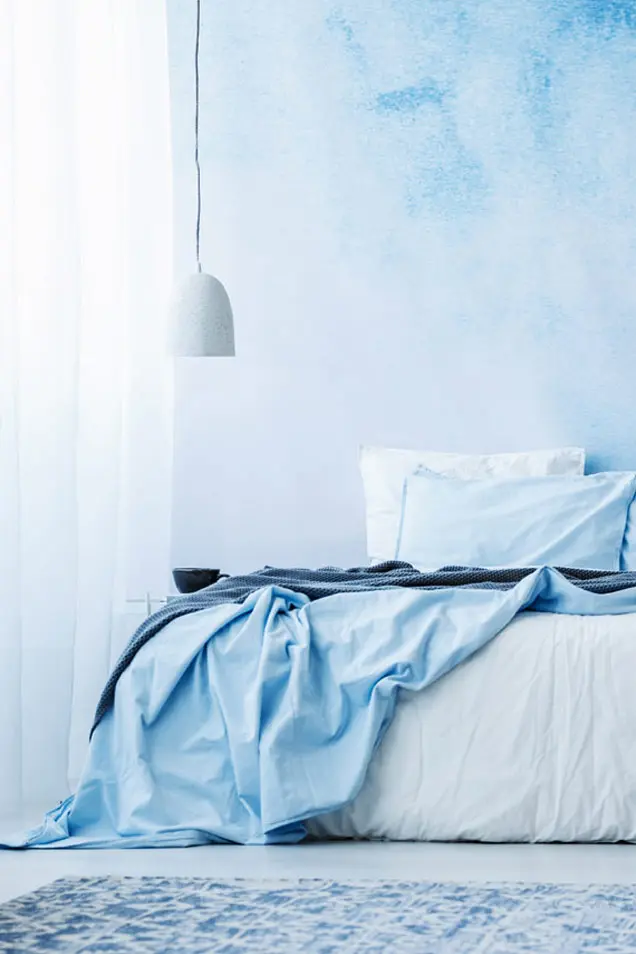 Dormitorio con pared revestida con estuco veneciano en tonos azules claros