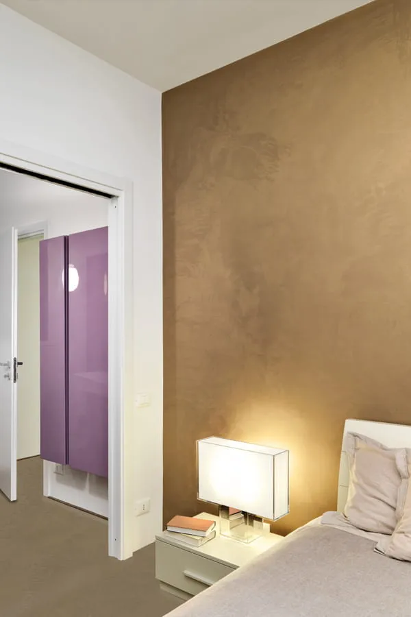 Dormitorio decorado con pared microcemento dorado