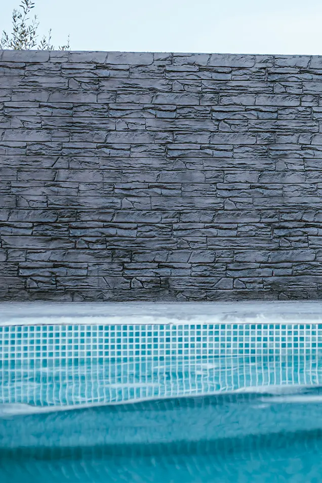 Piscina con hormigón impreso en la pared exterior con forma de piedra natural.