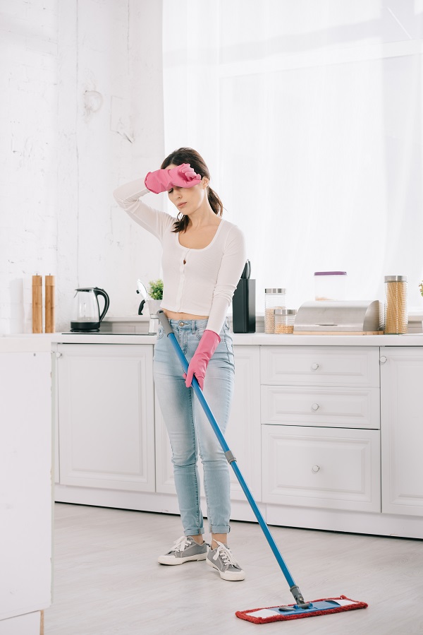 Mujer con mopa limpiando suelo de microcemento cansada