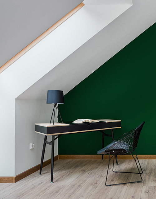 Pintura verde en la pared de un estudio equipado con un escritorio de color negro 
