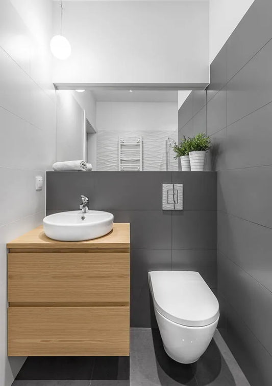 Baño con baldosas grandes pintadas en color gris.