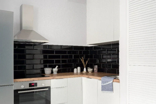 Cocina moderna con azulejos negros pintados y muebles blancos