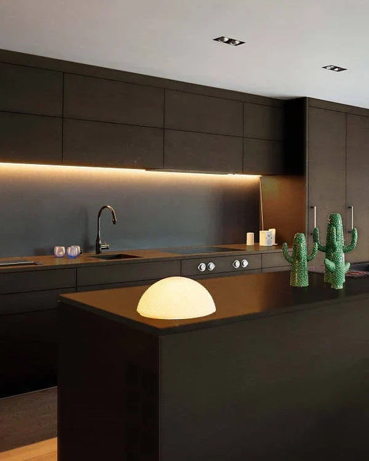 Cocina moderna con microcemento oscuro en paredes y mobiliario negro minimalista.