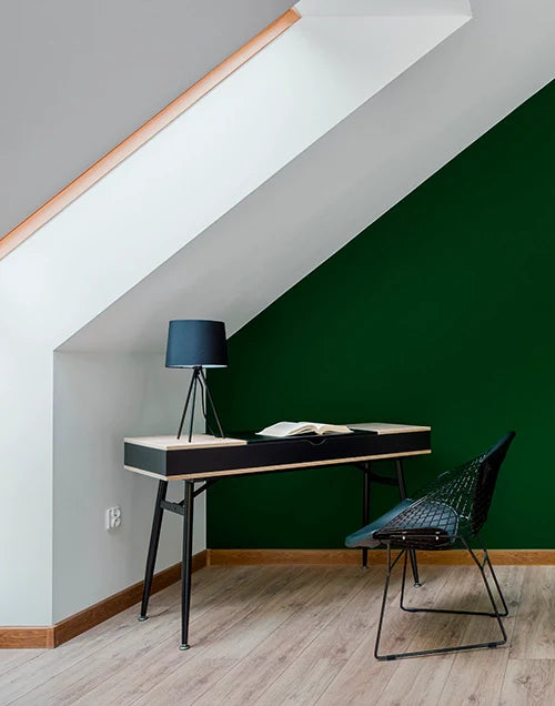 Despacho abuhardillado con pared pintada en color verde intenso.