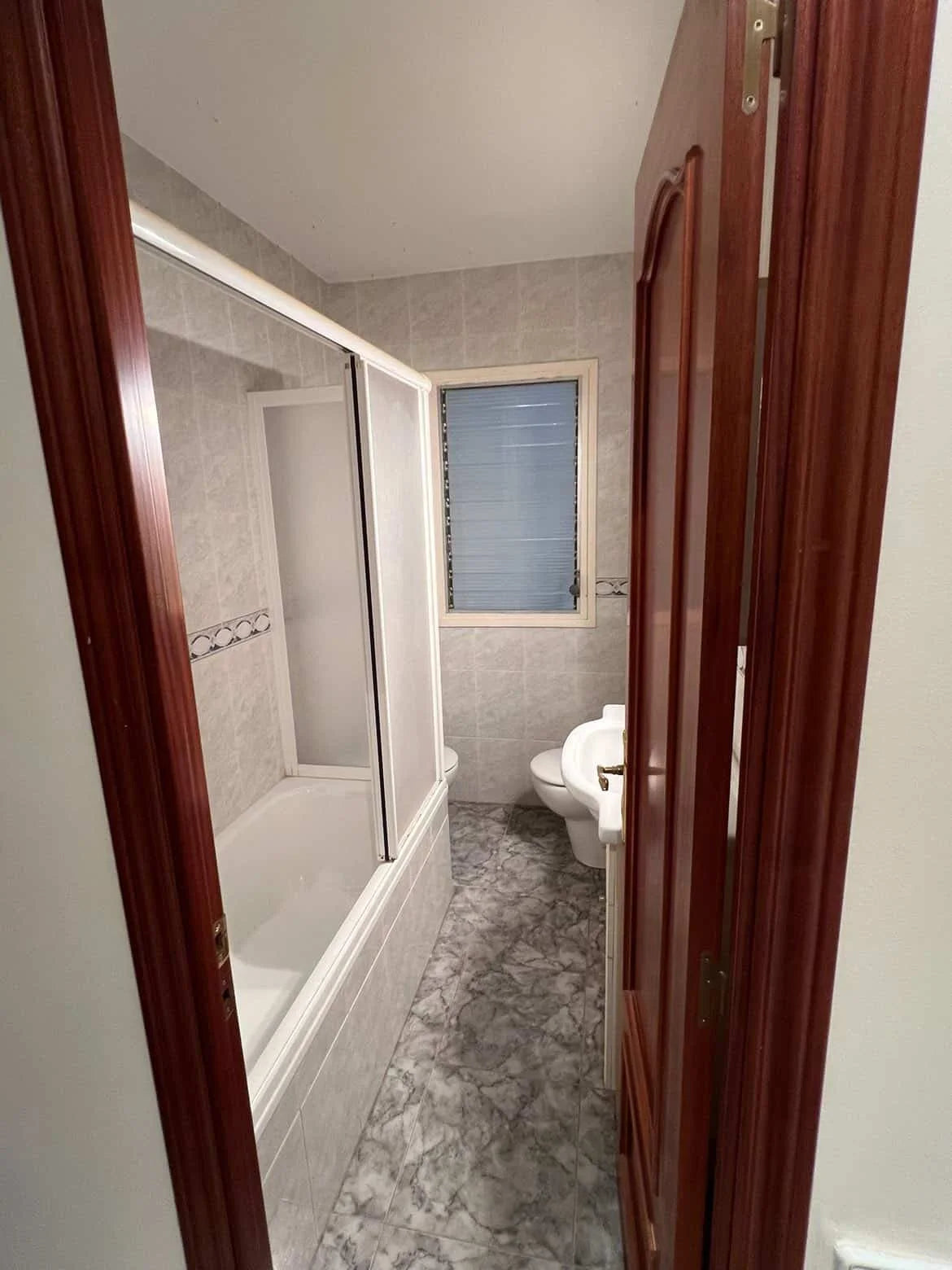 Baño antiguo con baldosas viejas en paredes y suelo.