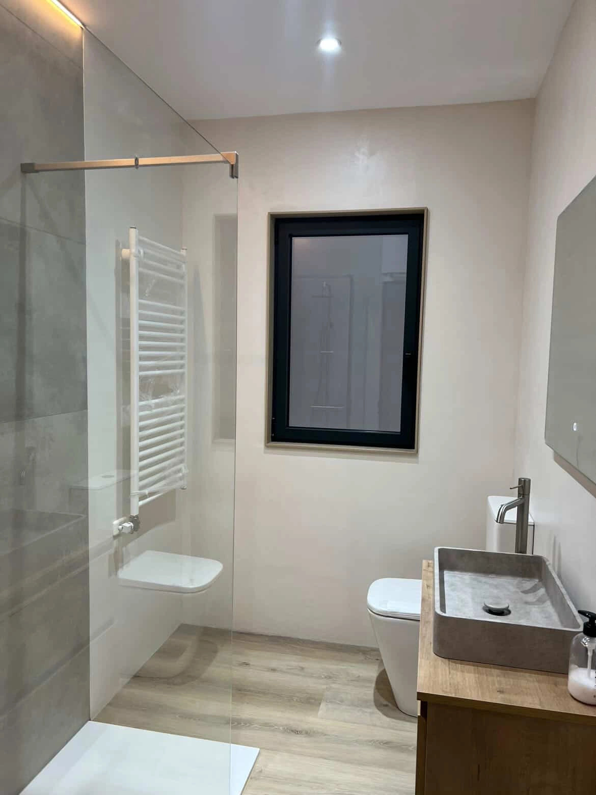 Reforma de baño con microcemento de la tienda Smartcret en el que se han cubierto las viejas baldosas de las paredes y suelo.