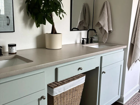 Encimera de baño de microcemento en color Universe, con lavabo integrado, espejos y decoración natural.