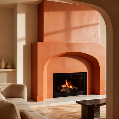 Chimenea de obra con microcemento color Coral con arco profundo; fuego encendido, suelo en espiga y sombras del ventanal.