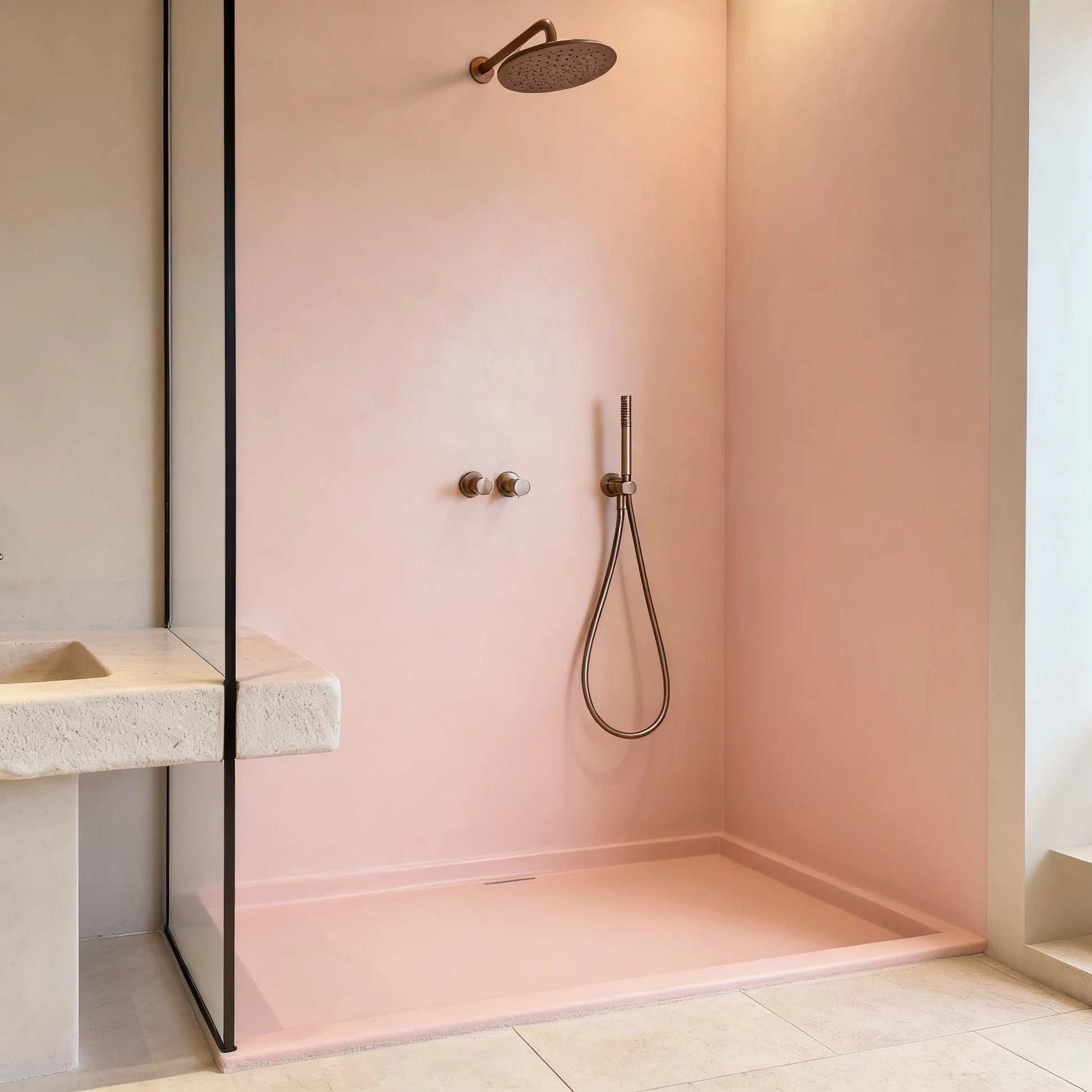 Ducha de obra con microcemento color Bush con grifería dorada, mampara de cristal y lavabo de piedra tallada.