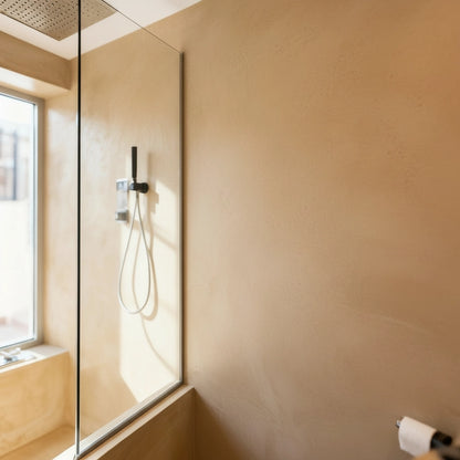 Ducha revestida con microcemento color India, iluminada por la luz natural que entra a través de la ventana.