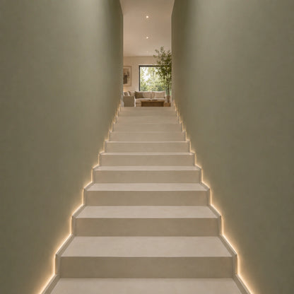 Escaleras revestidas de microcemento en color Porcelain con iluminación LED lateral y acceso a salón de diseño contemporáneo.