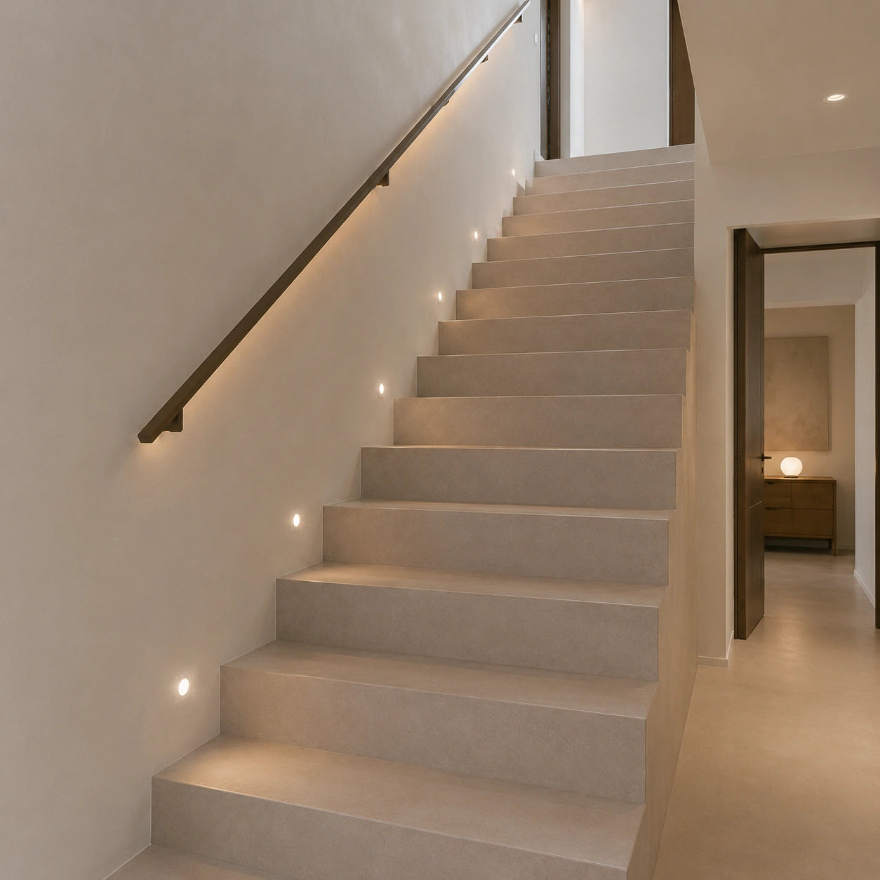 Planta baja de casa moderna con escalera recta revestida en microcemento beige color Spike con iluminación integrada.