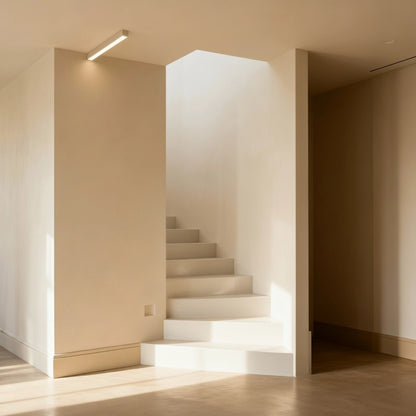 Escalera de obra revestida con microcemento color Blanco Roto y luz cenital que dibuja sombras suaves