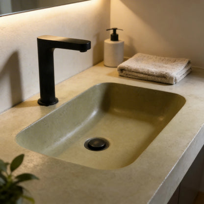 Lavabo de microcemento color Khaki con acabado liso y sedoso, integrado en encimera de obra, grifería negra mate y decoración minimalista.