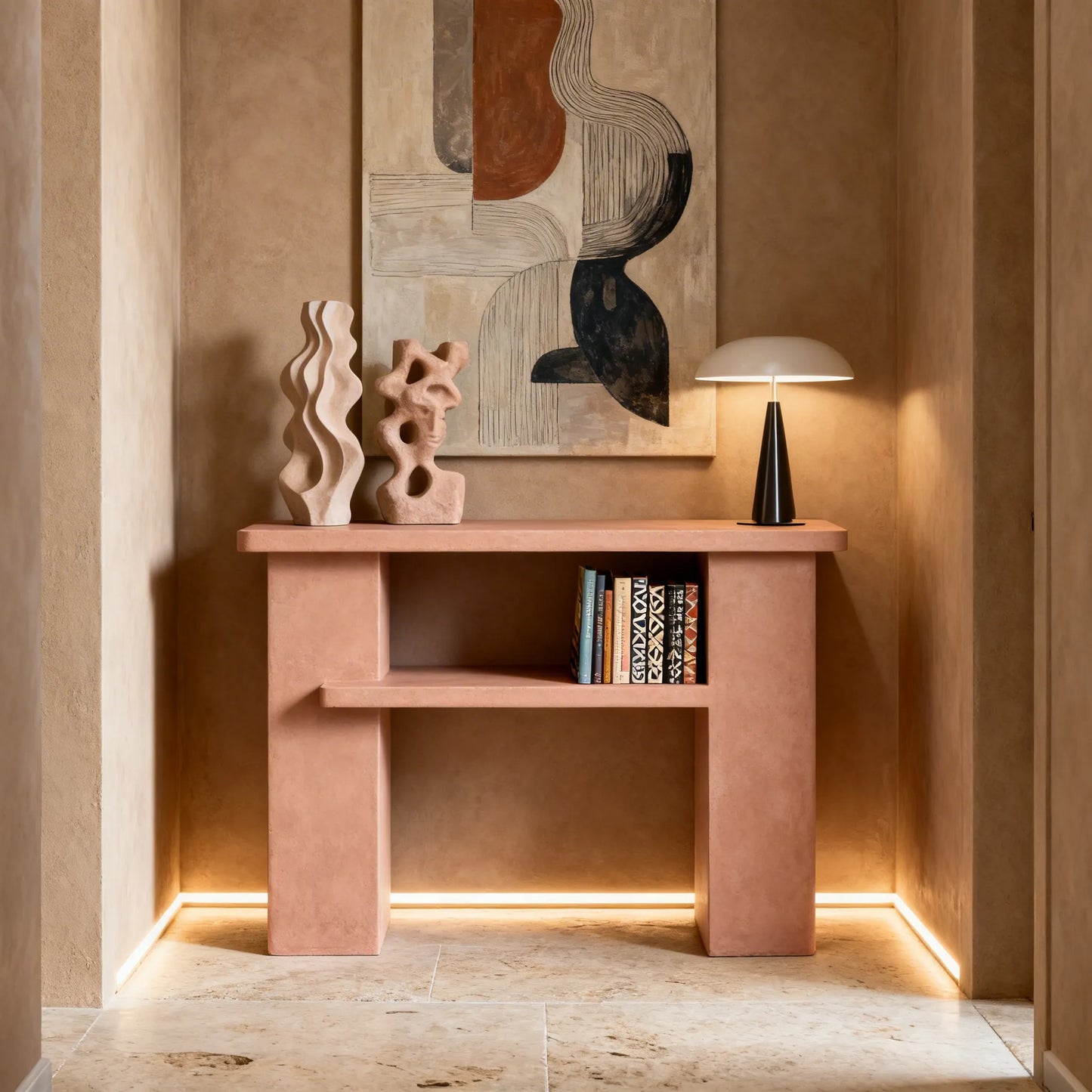 Consola de microcemento en color Blush con balda central, situada en un recibidor con paredes en tonos cálidos y suelo de piedra natural. 