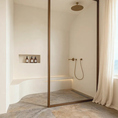 Baño con paredes de microcemento color Blanco Roto con banco curvo integrado sobre suelo cerámico efecto piedra.