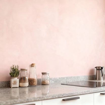 Pared de cocina en microcemento color Blush con encimera de granito y tarros decorativos sobre la superficie.