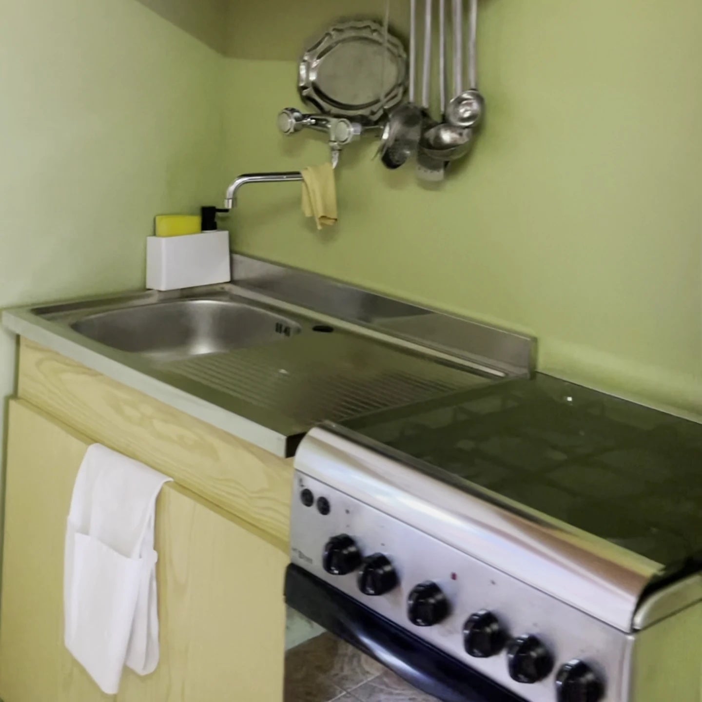 Pared frontal de cocina con microcemento Smartcret color Wasabi junto a fregadero y zona de cocción.