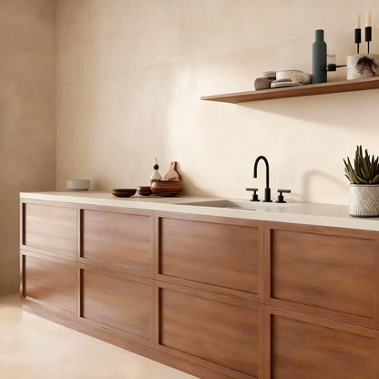 Pared de cocina en microcemento color Bone con encimera clara, muebles de madera y estante superior con decoración minimalista.
