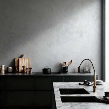 Pared de cocina de microcemento color Universe, luz natural y encimera de mármol con grifería dorada.