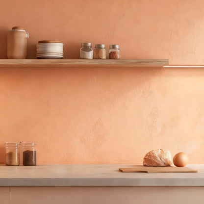 Pared de cocina en microcemento color Salmon, luz cálida y encimera clara con pan y tarros de cristal.