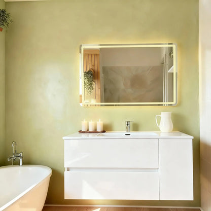 Pared de baño en microcemento color Wasabi con mueble blanco, bañera curva y luz cálida que realza el ambiente.