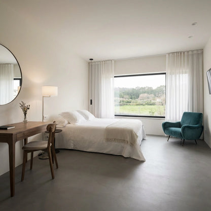 Dormitorio luminoso con suelo de microcemento color Shale Grey y gran ventanal con vistas al paisaje.