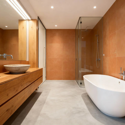 Baño rectangular con suelo de microcemento color Universe, paredes con baldosas en tono terracota y mueble de madera.