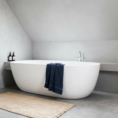 Baño minimalista con bañera exenta y suelo de microcemento color Universe, creando un ambiente suave y relajante.