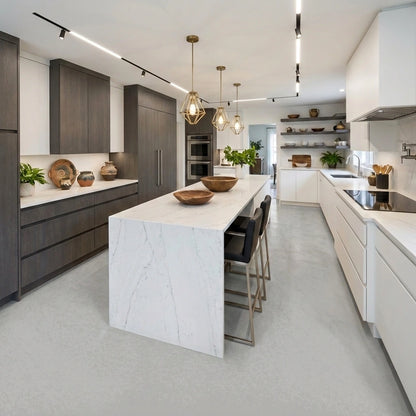Cocina amplia con suelo continuo de microcemento gris color Universe, isla central clara, mobiliario en blanco y gris oscuro, y estanterías decorativas.