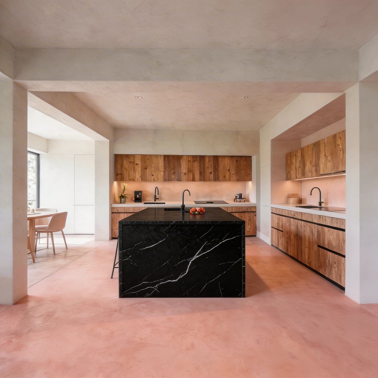 Amplia cocina abierta con isla central de encimera negra de mármol y suelo continuo de microcemento color Coral de Smartcret.