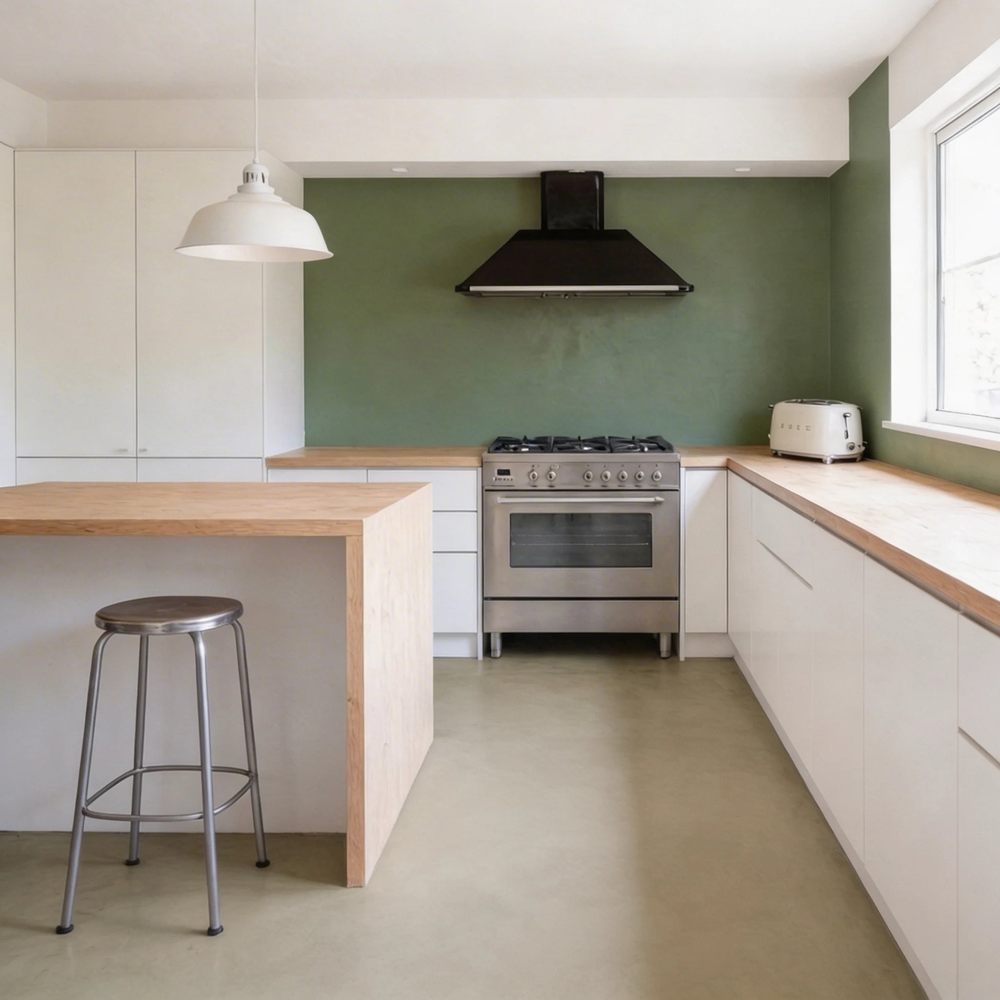 Cocina en L con suelo de microcemento gris verdoso color Liquen de Smartcret y muebles blancos con encimera de madera.