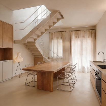 Cocina abierta con comedor integrado y suelo continuo de microcemento color Café de Smartcret, conectada con la planta superior mediante una escalera. 